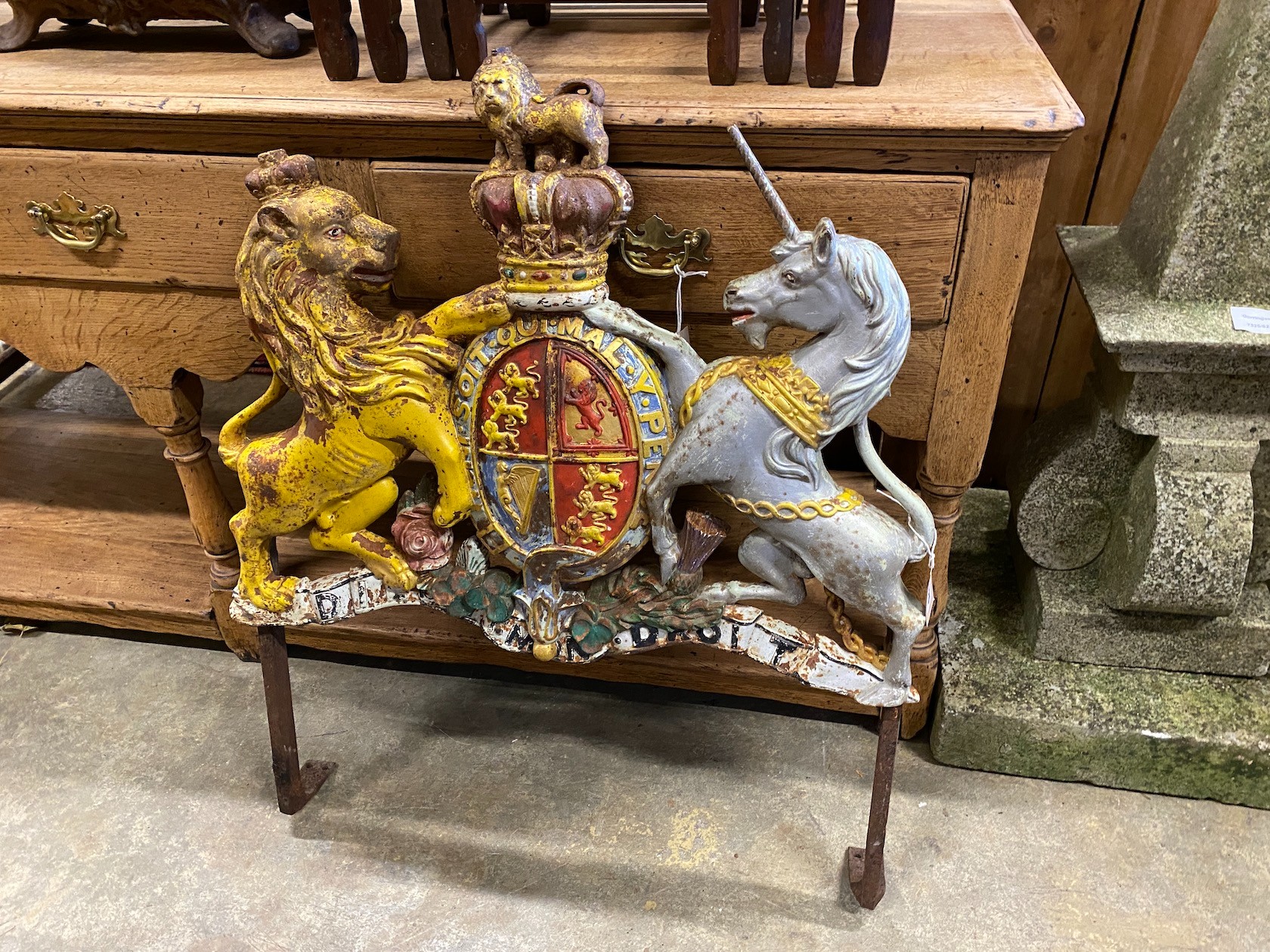 A Victorian painted cast iron Royal Coat of Arms, on later wrought iron stand, width 69cm, height 86cm